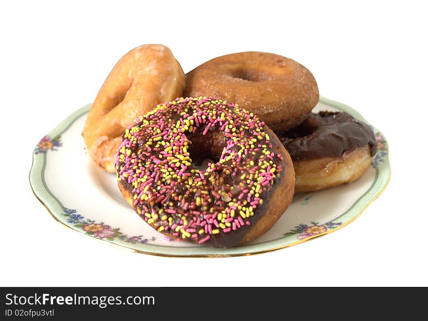 Assorted doughnuts, honey dipped, chocolate, sugar and sprinkled all arranged on a china dish.