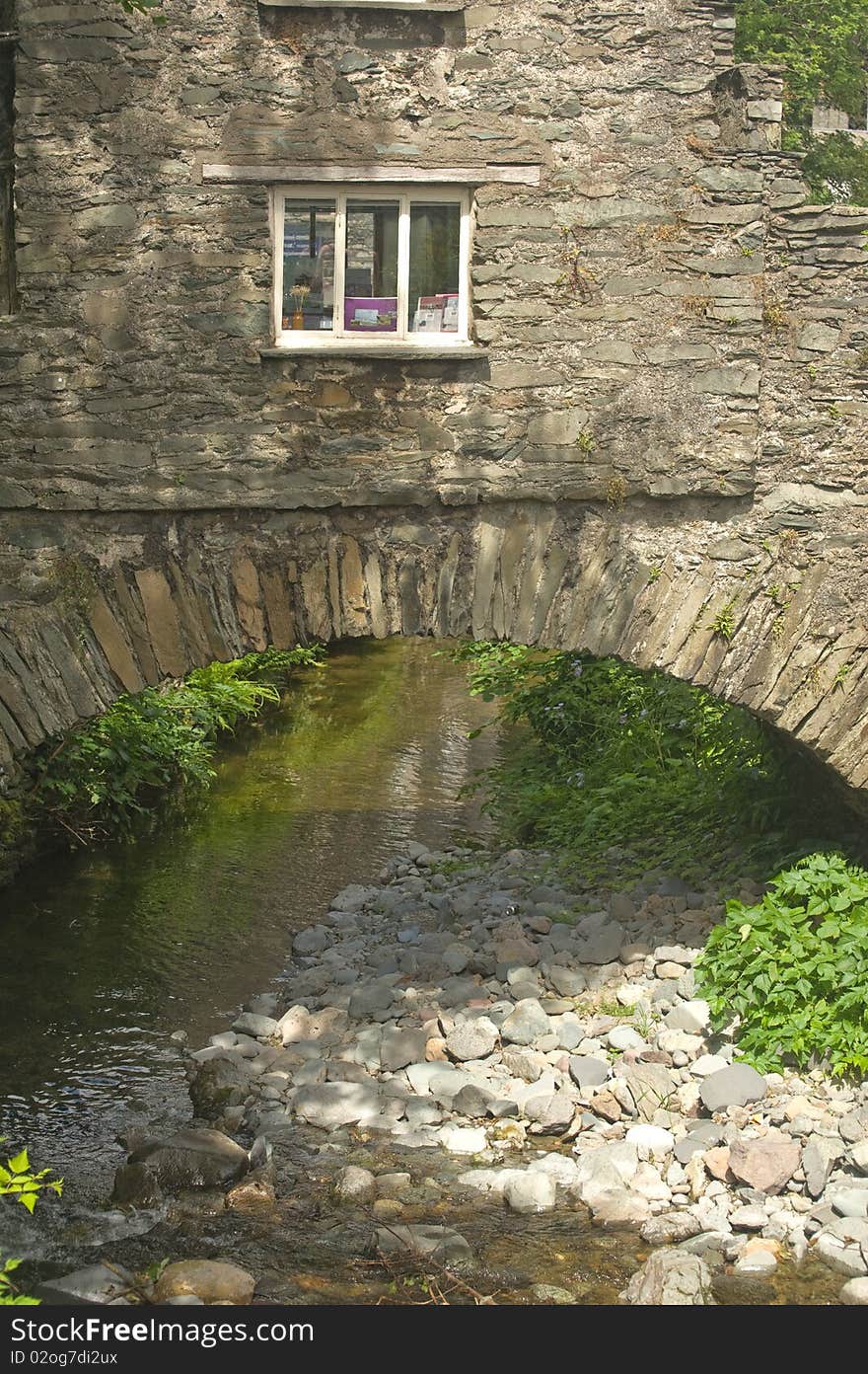 An image of a small stone built house constructed over a river. An image of a small stone built house constructed over a river.