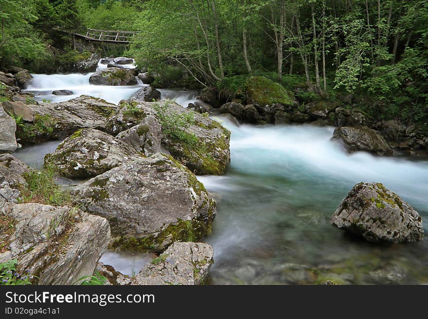 A small wooden bridge along the riverside of Santantonio river, in Santantonio's Valley, Lombardy, Italy.