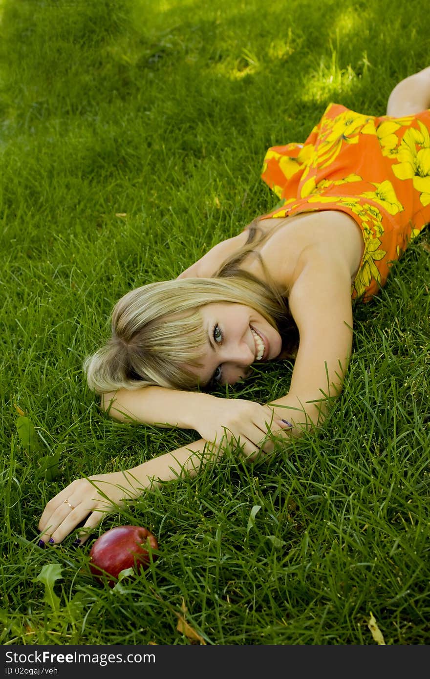 Girl with an apple on a green lawn