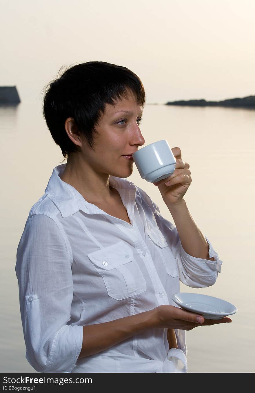 Young woman meets sunrise drinking morning coffee