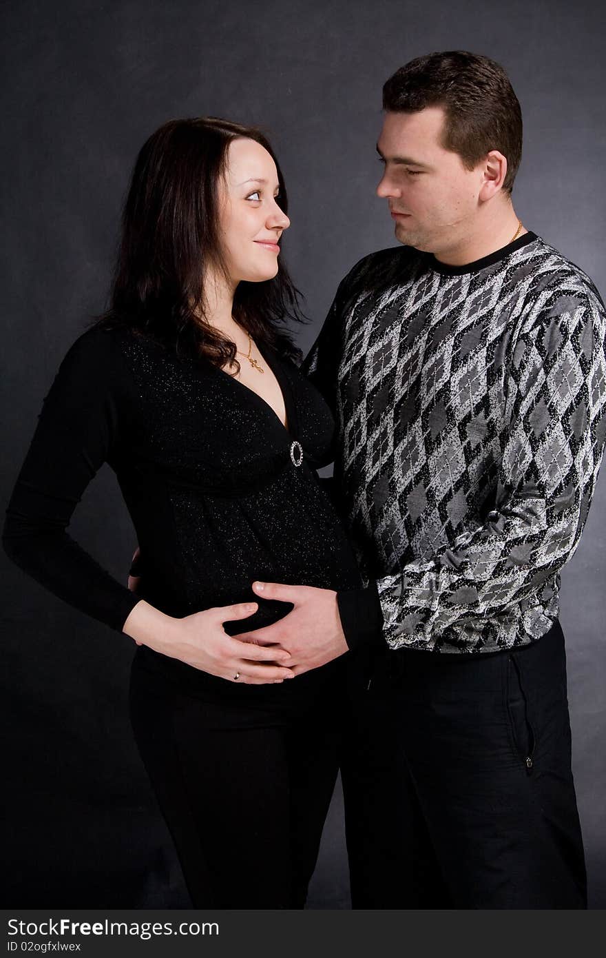 Pregnant couple posing on dark background. Pregnant couple posing on dark background