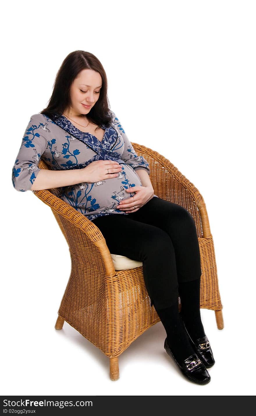 Pregnant woman sitting on a wicker chair and hugs belly, isolated on white. Pregnant woman sitting on a wicker chair and hugs belly, isolated on white