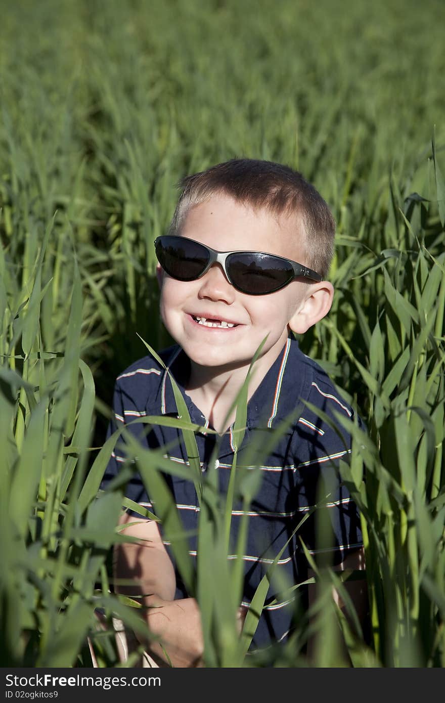 Boy with sunglasses in tall oat field