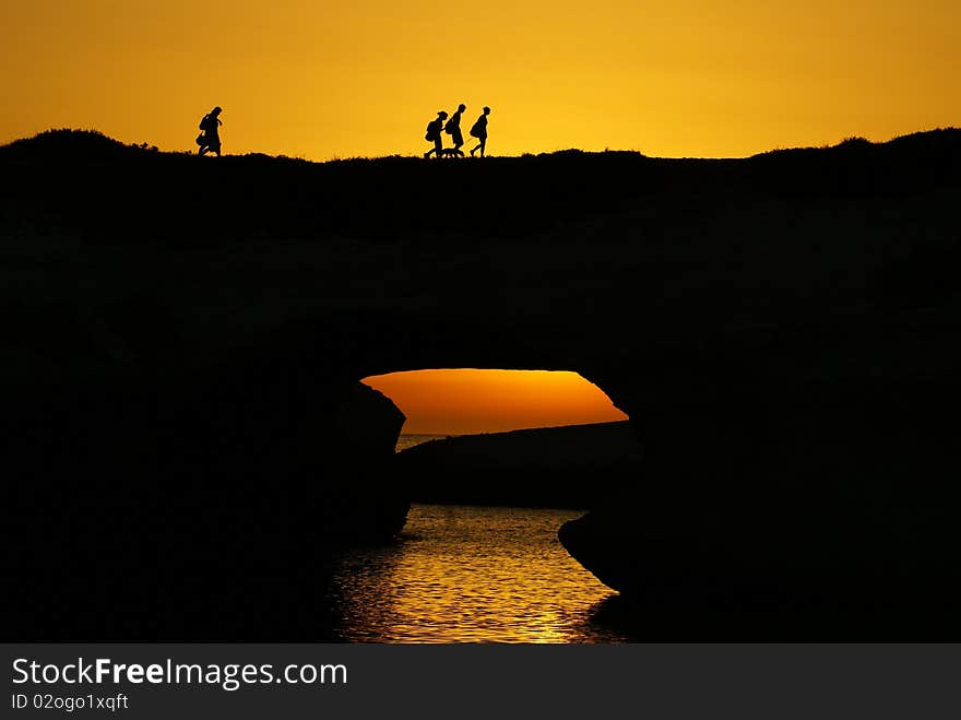 Silhouettes of people over the sea in the sunset