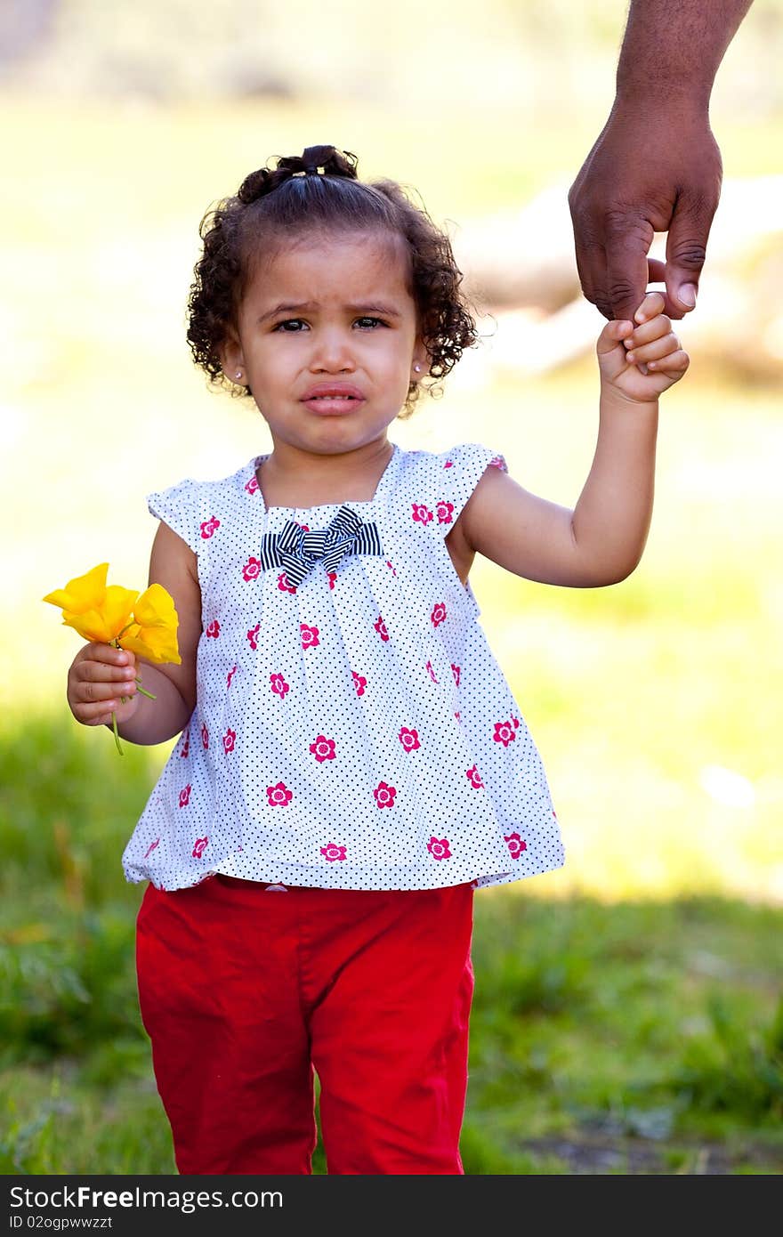 A very young african american (black) girl holds some flowers while wearing a white and red outfit. A very young african american (black) girl holds some flowers while wearing a white and red outfit.