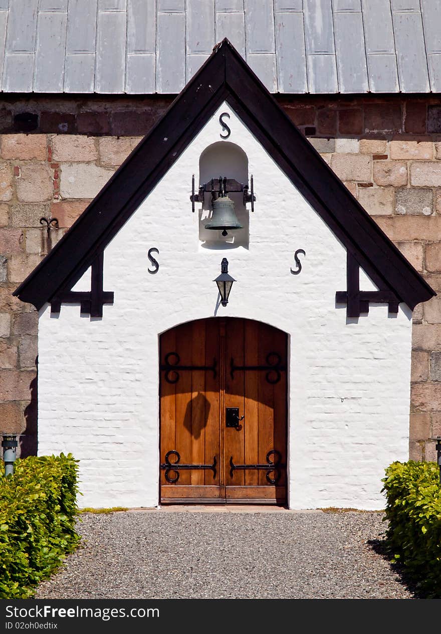 White gable from church entrance with beautiful door and church bell. White gable from church entrance with beautiful door and church bell.