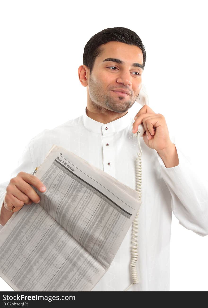 An ethnic mixed race man on a telephone call.  He is holding a finance newspaper and wearing traditional middle eastern clothing.  Newspaper data has been blurred.  White background. An ethnic mixed race man on a telephone call.  He is holding a finance newspaper and wearing traditional middle eastern clothing.  Newspaper data has been blurred.  White background.