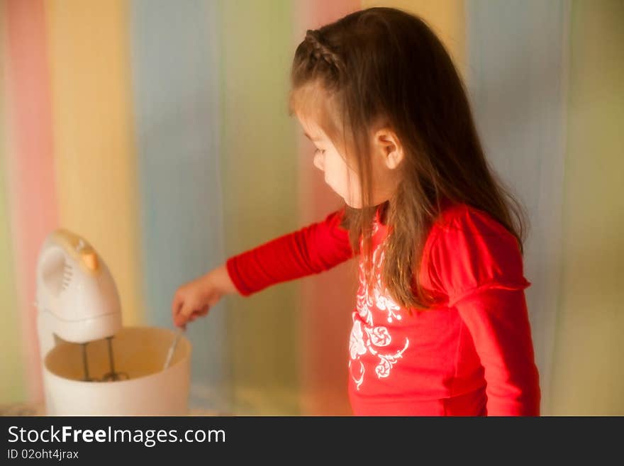 Girl helping her mother to cook apple pie in the kitchen. She is mixing eggs with sugar in the mixer. Girl helping her mother to cook apple pie in the kitchen. She is mixing eggs with sugar in the mixer