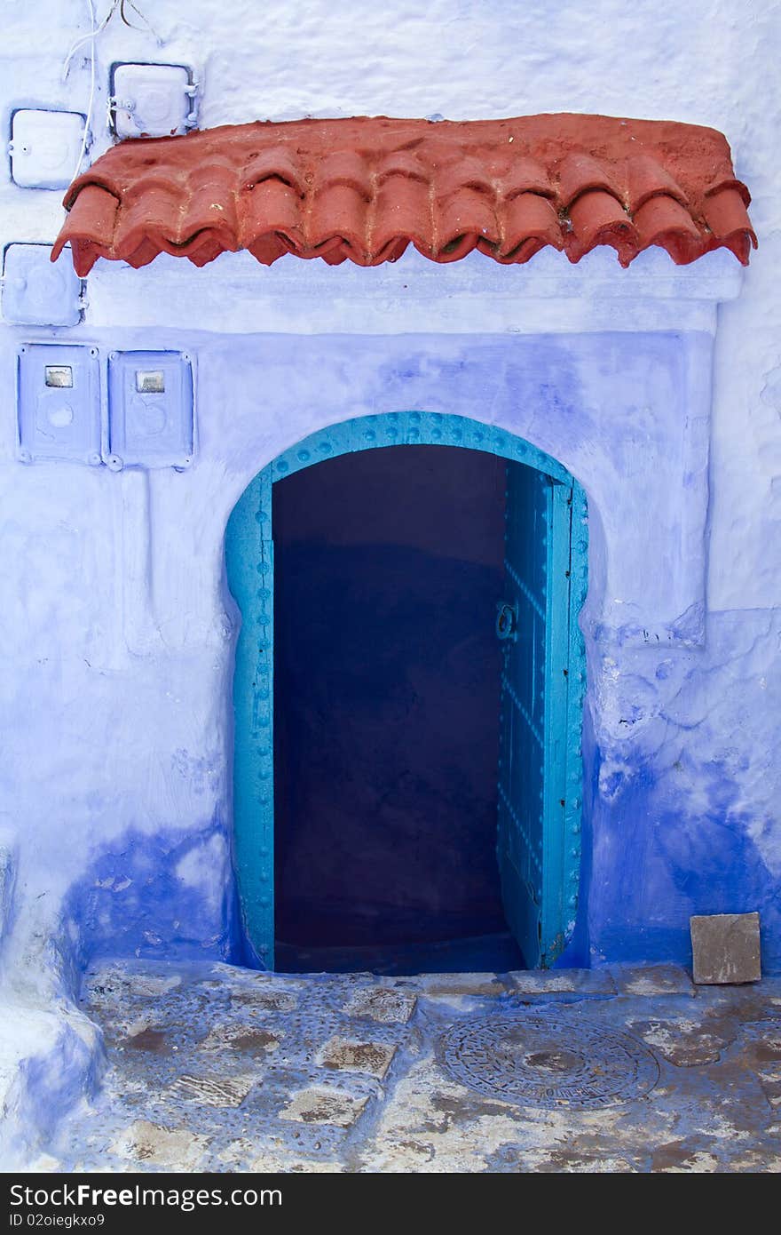 Typical street in the town of Chefchaouen in Morocco. Doorway with red terra-cotta tiles above doorway. Typical street in the town of Chefchaouen in Morocco. Doorway with red terra-cotta tiles above doorway.