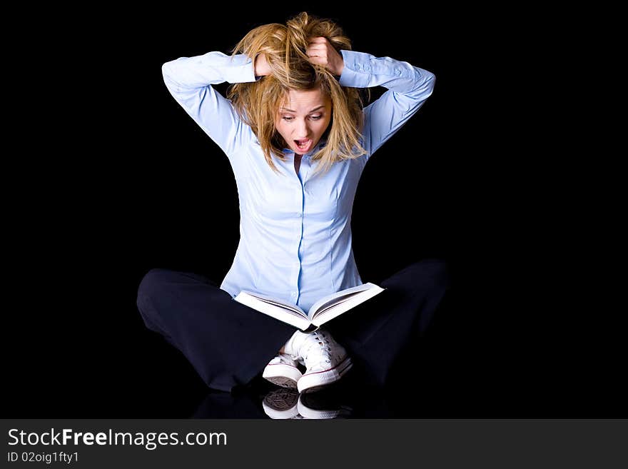 Young female student thrilled and frightened of what she reads in the book, studio shoot isolated on black background. Young female student thrilled and frightened of what she reads in the book, studio shoot isolated on black background