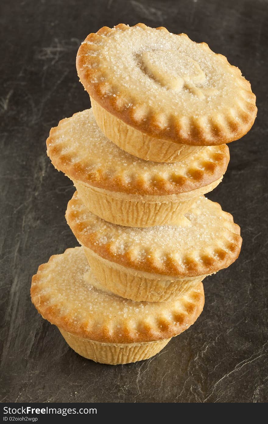 Four apple pies in a stack on a slate background