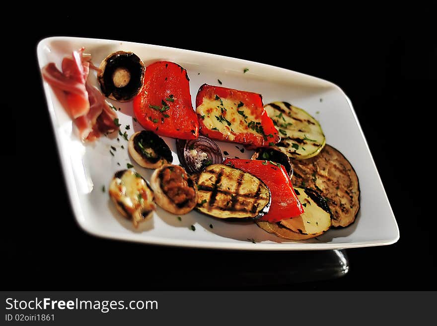 Mushroom appetizer with ham and pepper isolated on black