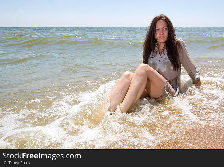 Young lady sitting in water of a sea