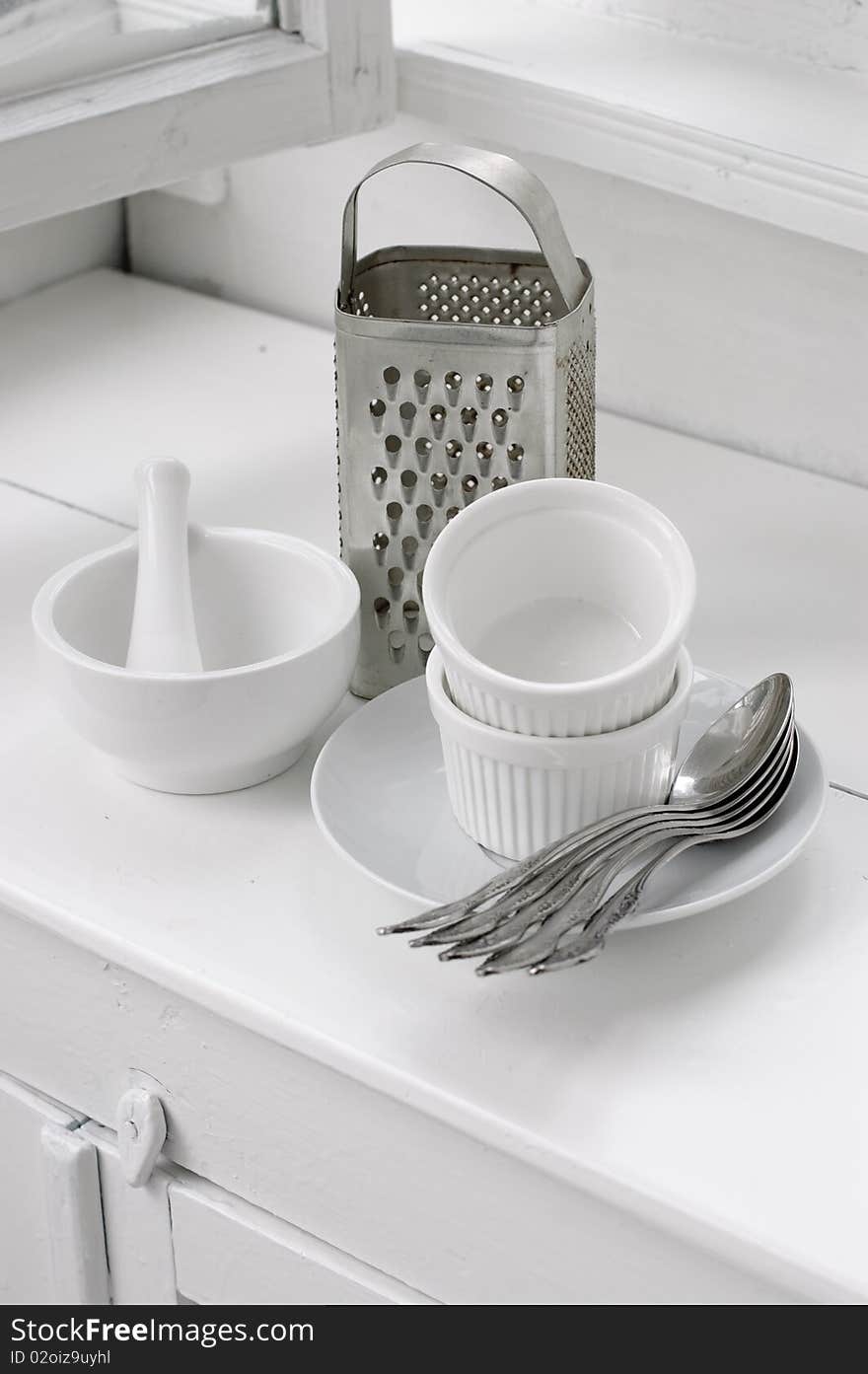 White ceramic and metal dishes on a white painted wooden floor