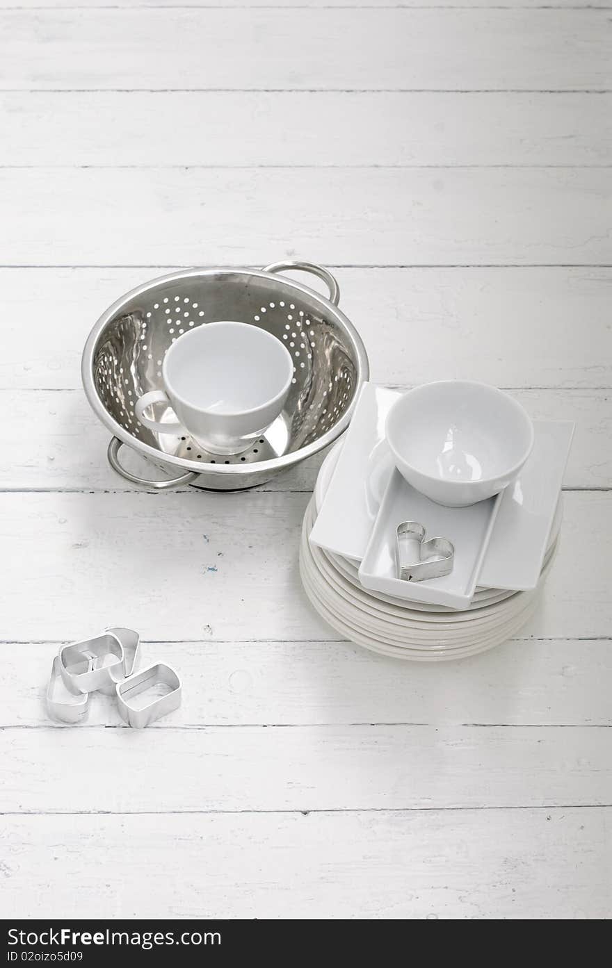 White ceramic and metal dishes on a white painted wooden floor