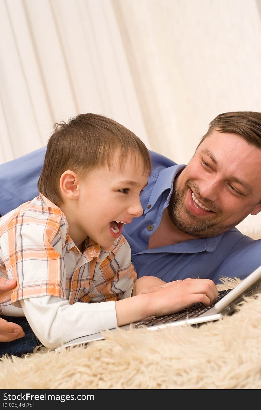 Father and son on the carpet with laptop