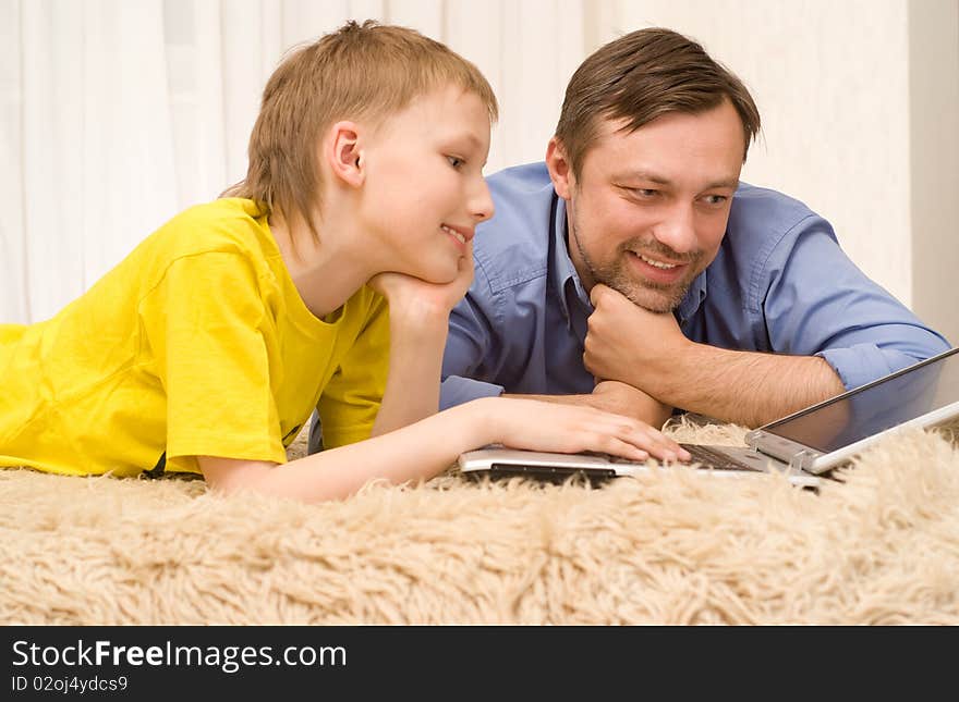 Father and son on the carpet with laptop. Father and son on the carpet with laptop