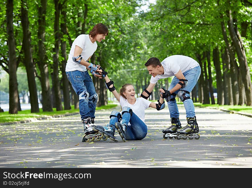 Two young men on roller lift a fallen girl. Two young men on roller lift a fallen girl