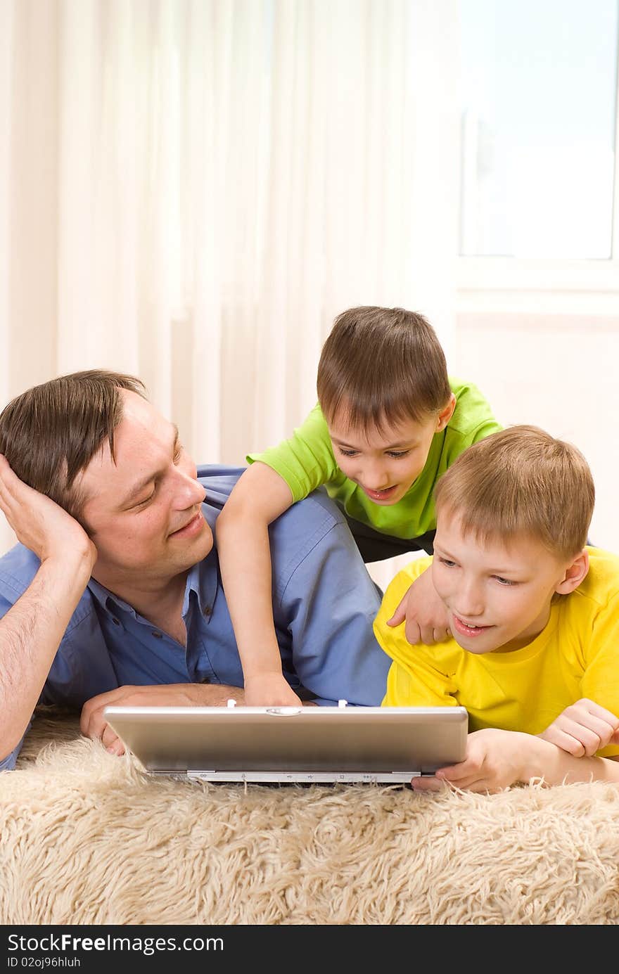 Father with his sons is on the carpet with laptop. Father with his sons is on the carpet with laptop