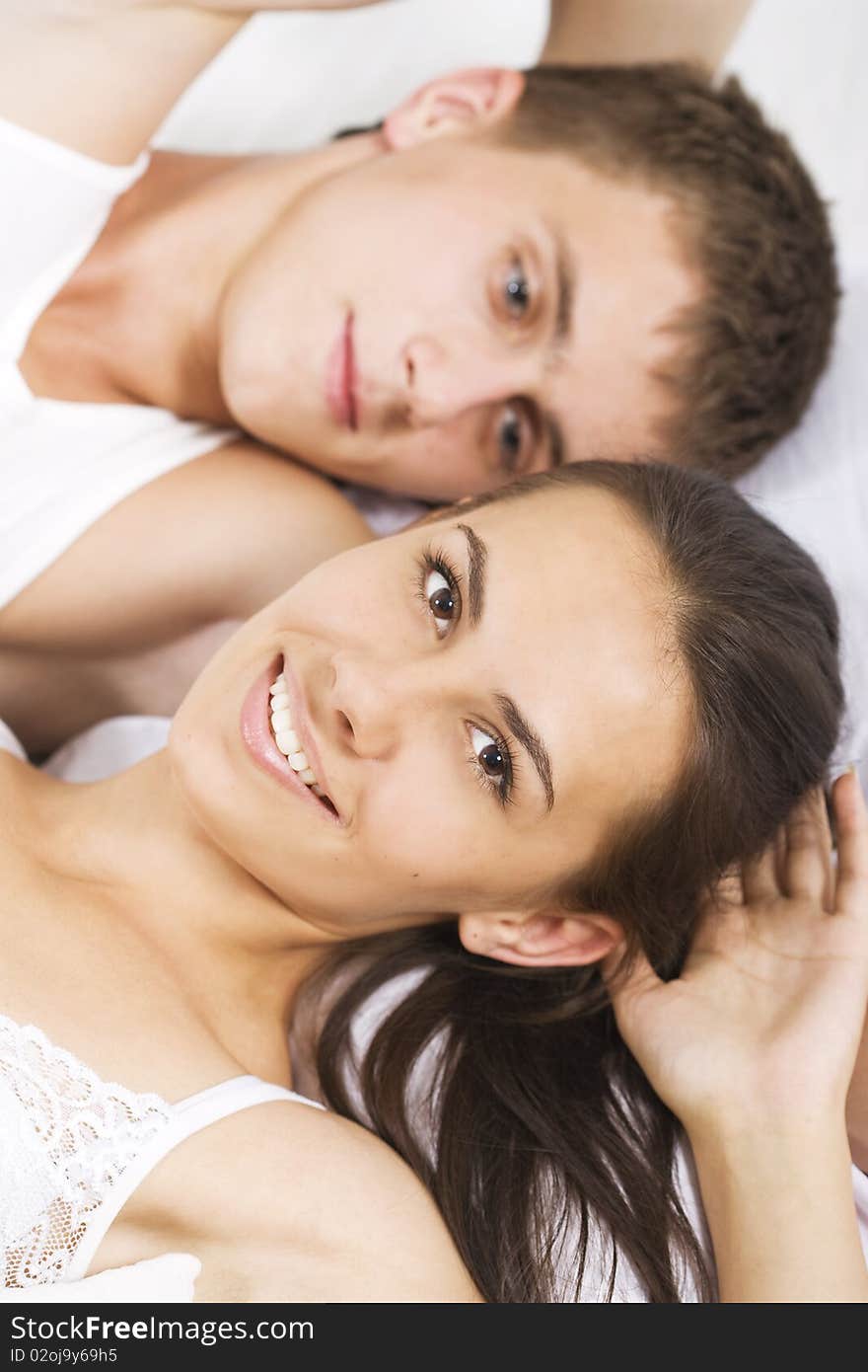 Young smiling couple in a bed on white sheets. Young smiling couple in a bed on white sheets