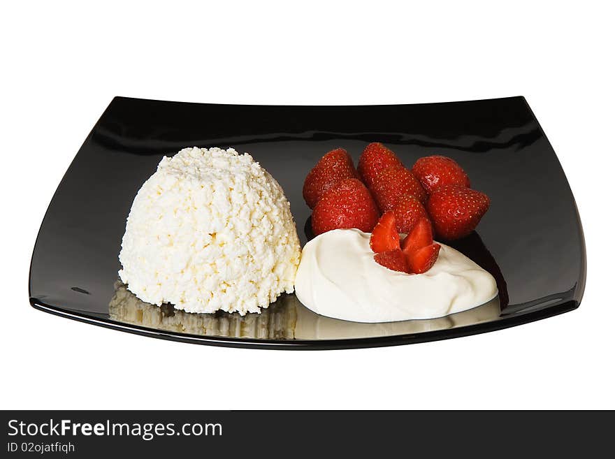 Cheese and strawberries with cream on black plate isolated on white background