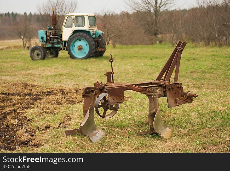 Old plow and tractor in village