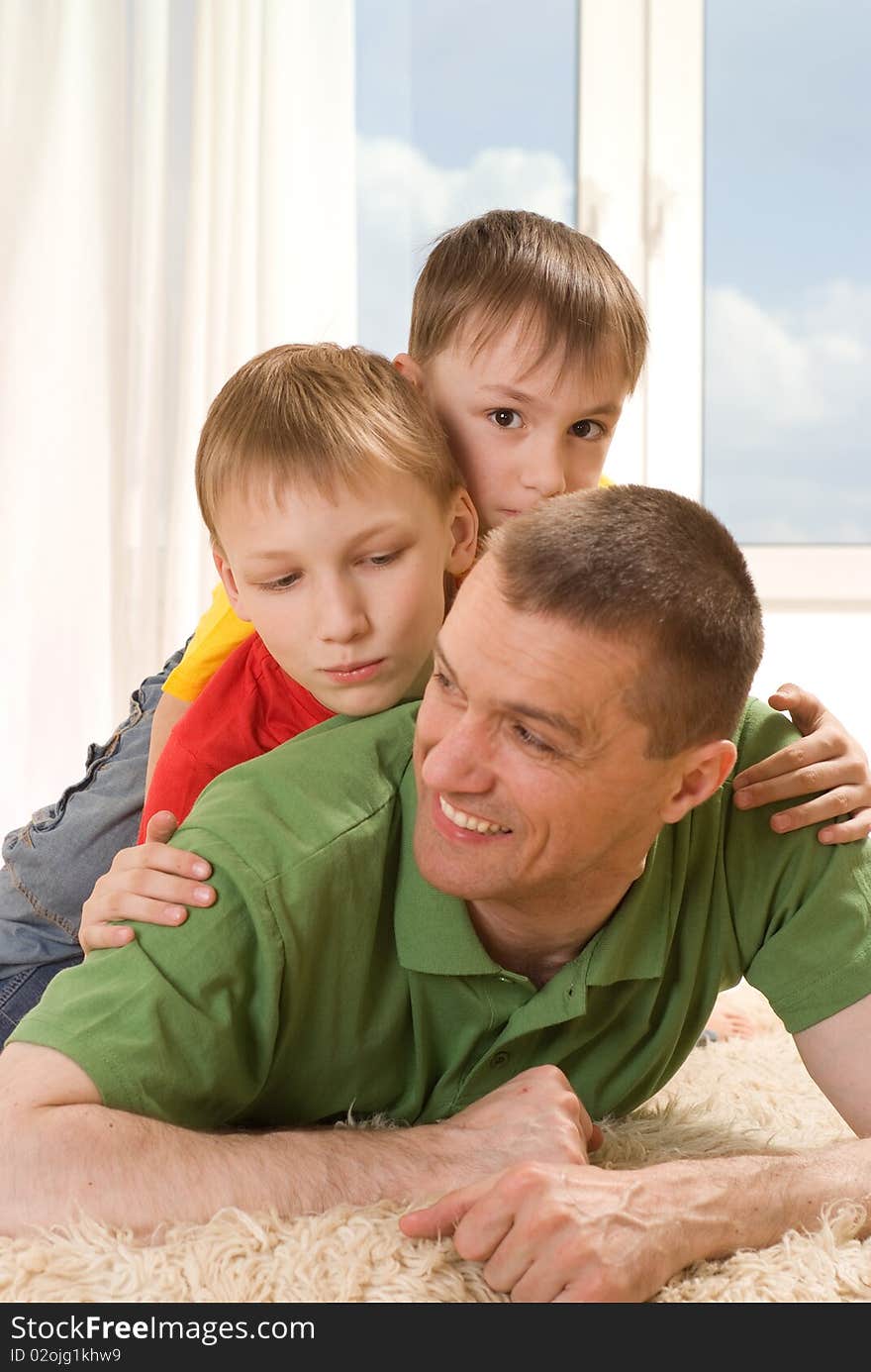 Father and two young brothers lying on the carpet