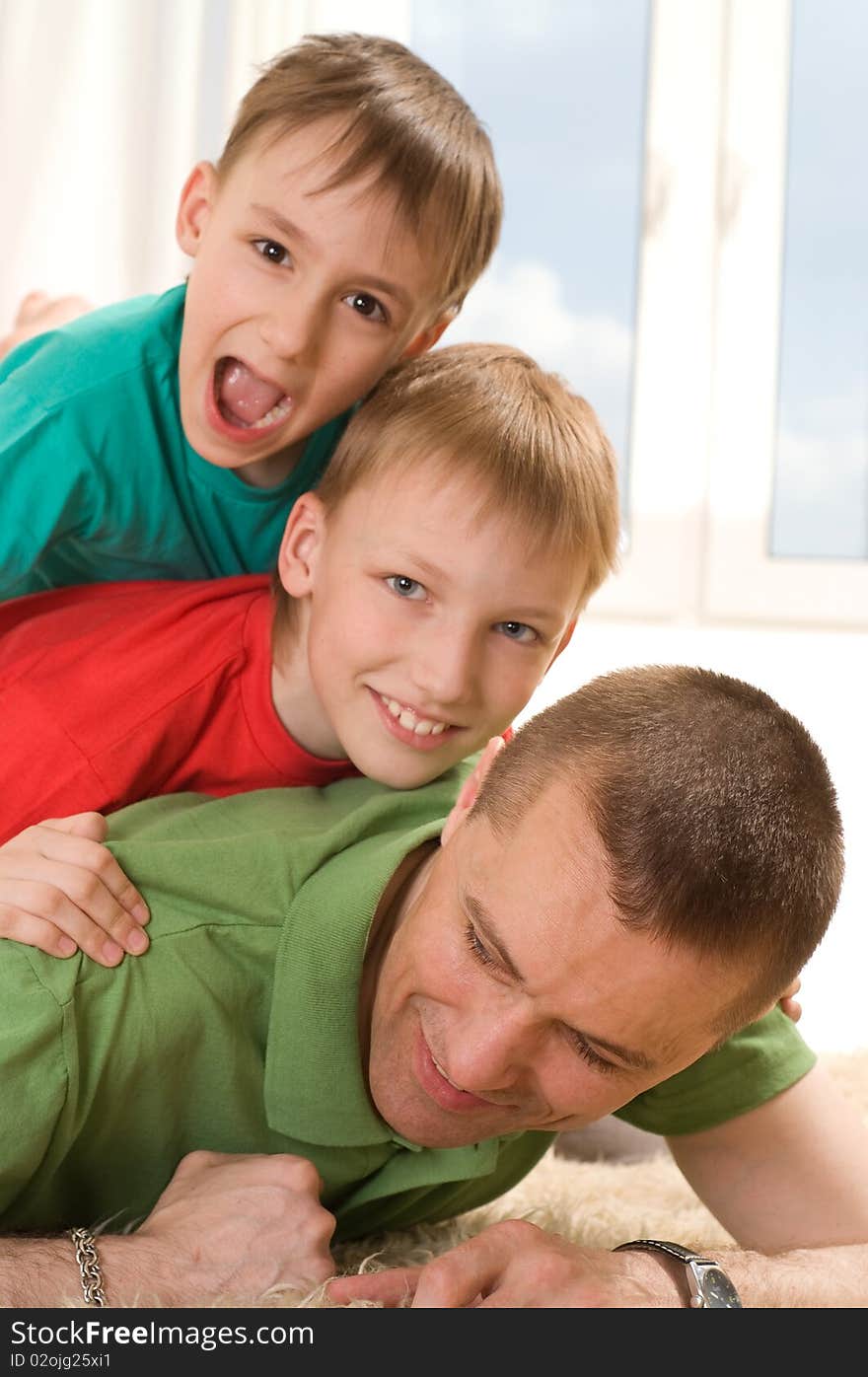 Father and two young brothers lying on the carpet