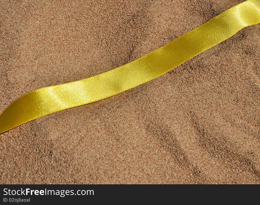 Yellow awareness ribbon on a asand background. Yellow awareness ribbon on a asand background