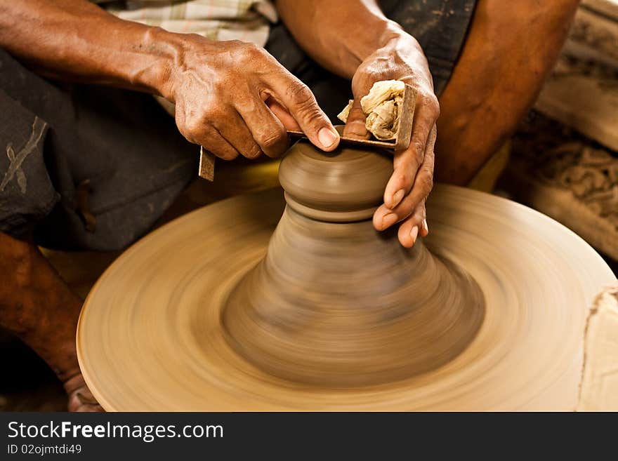 Potter's wheel and hands of craftsman hold a jug