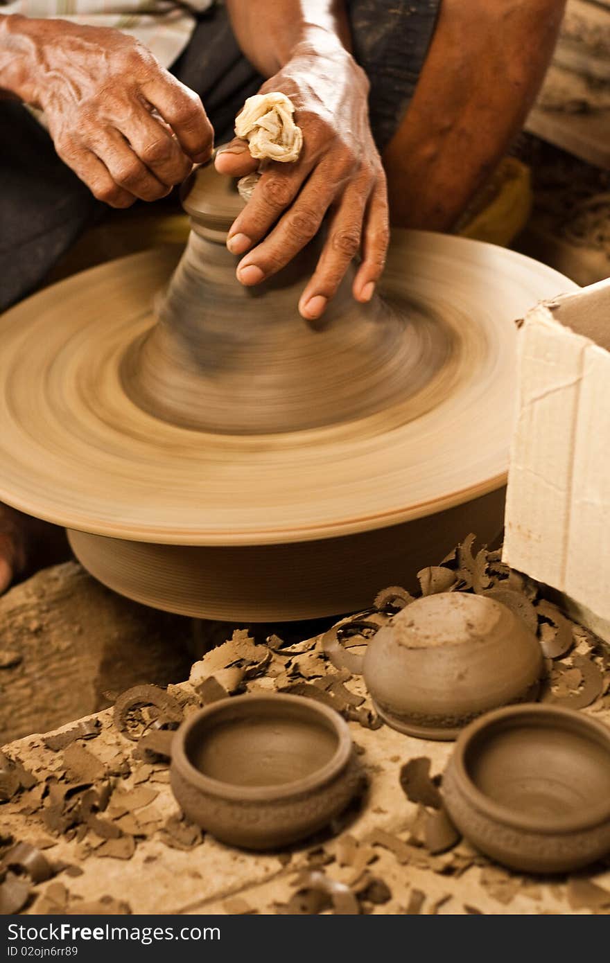 Potter's wheel and hands of craftsman hold a jug