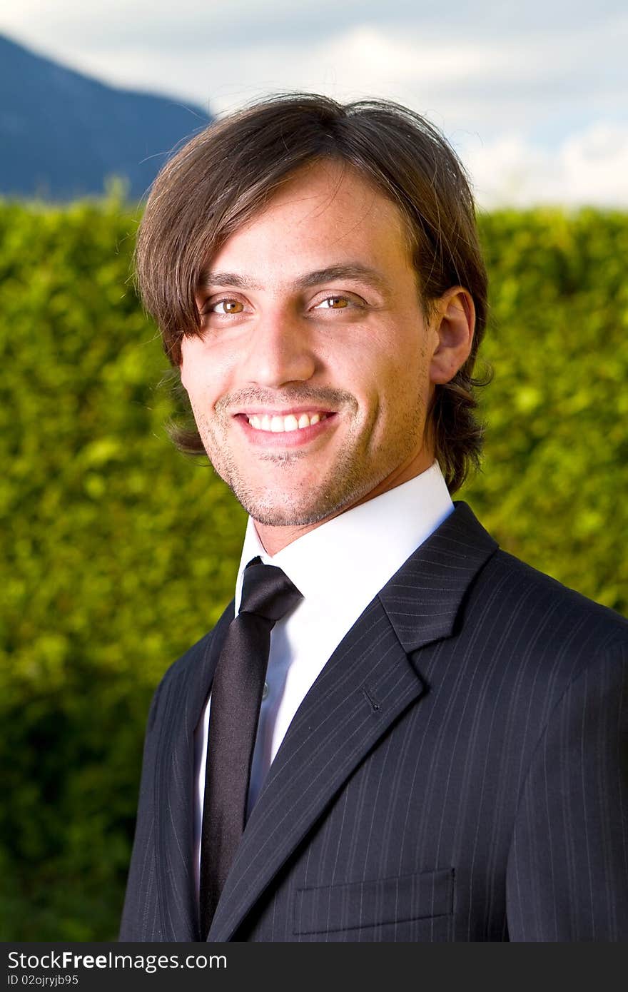 Young businessman with longer hair over a blue sky outside. Young businessman with longer hair over a blue sky outside.