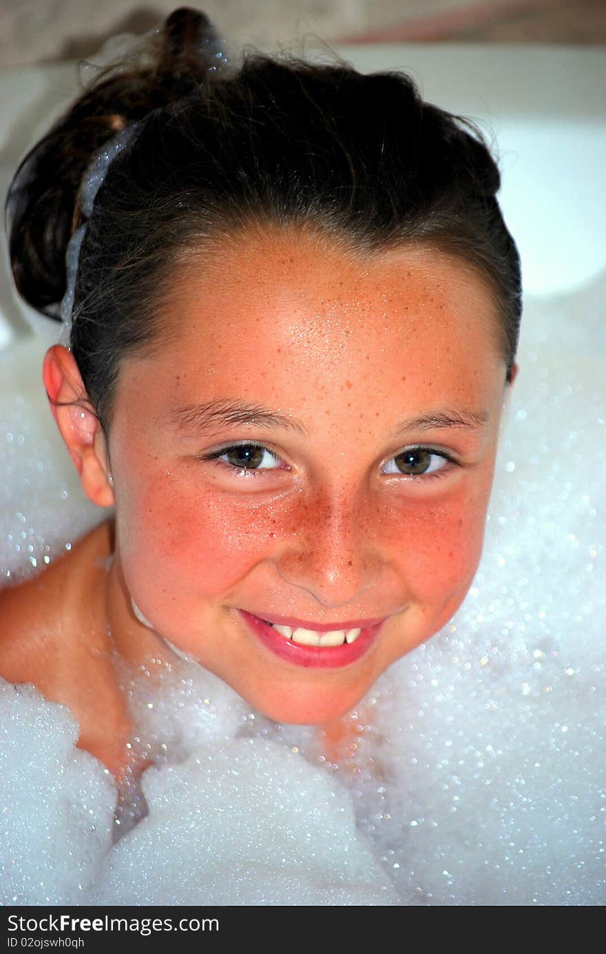 A young preteen girl that is surrounded by suds in a bubble bath. A young preteen girl that is surrounded by suds in a bubble bath.