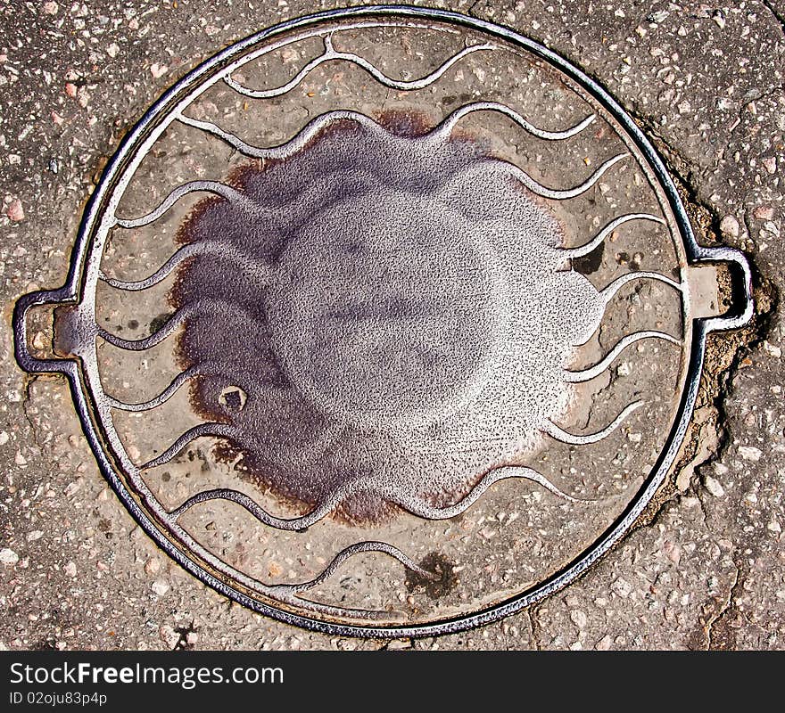 Old manhole cover in asphalt