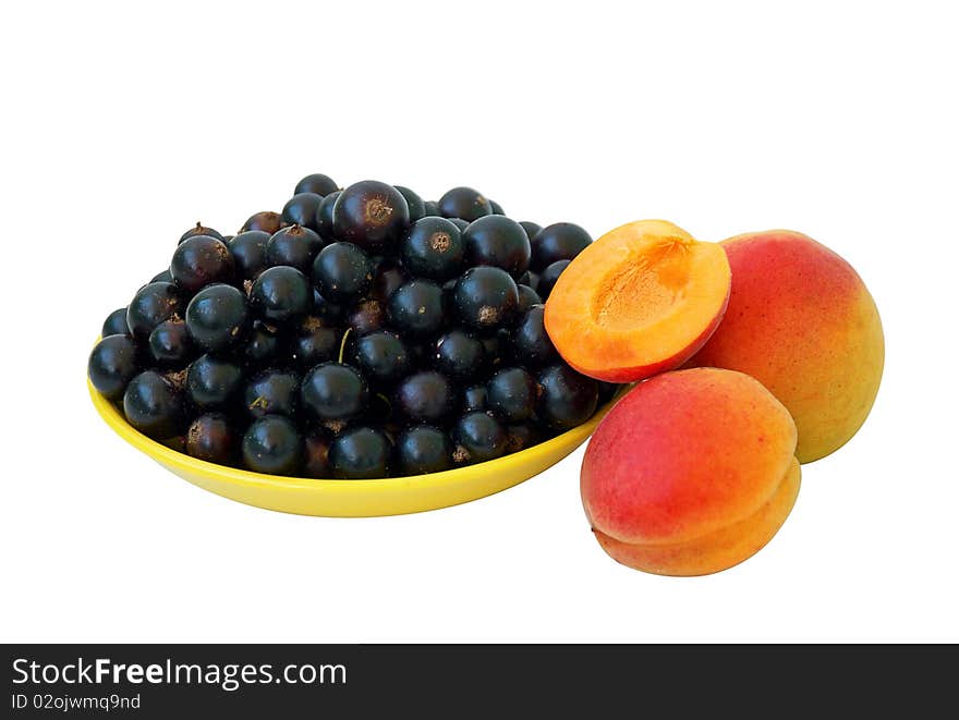 Black currant berries in yellow plate and apricots, isolated on white. Black currant berries in yellow plate and apricots, isolated on white