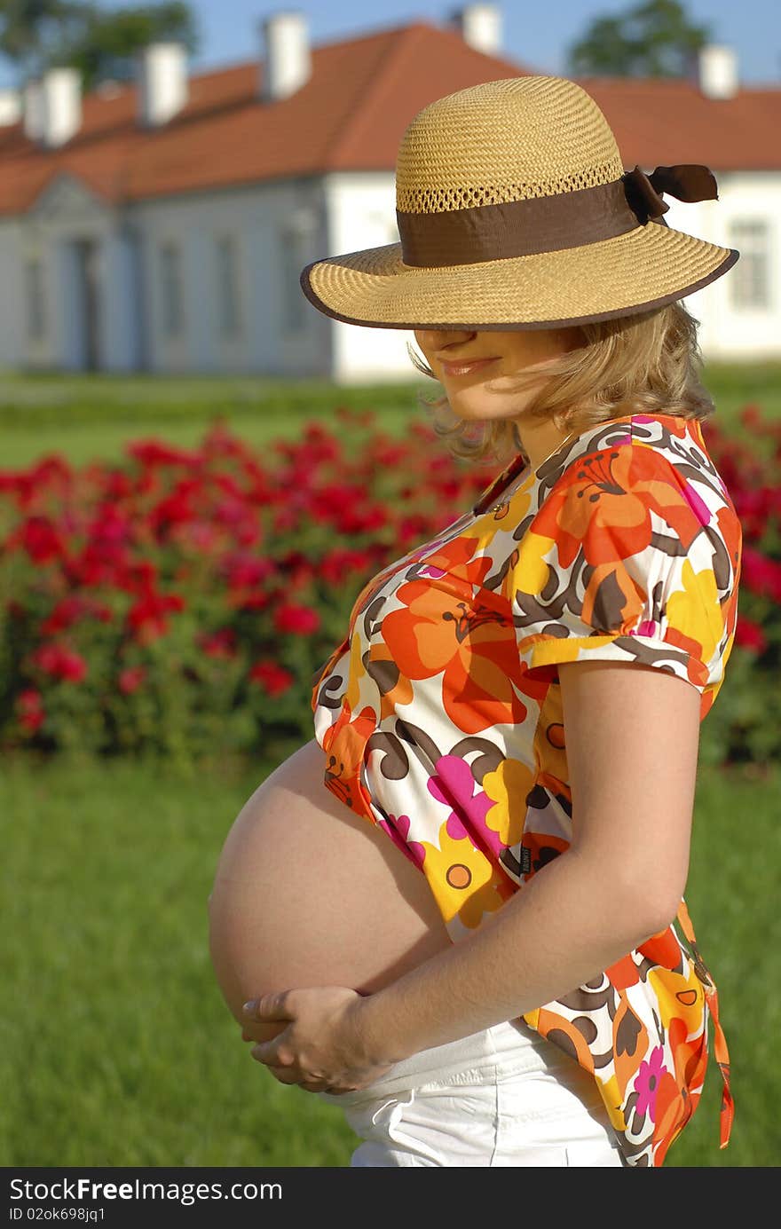 Pregnant woman with hands on the belly in the garden