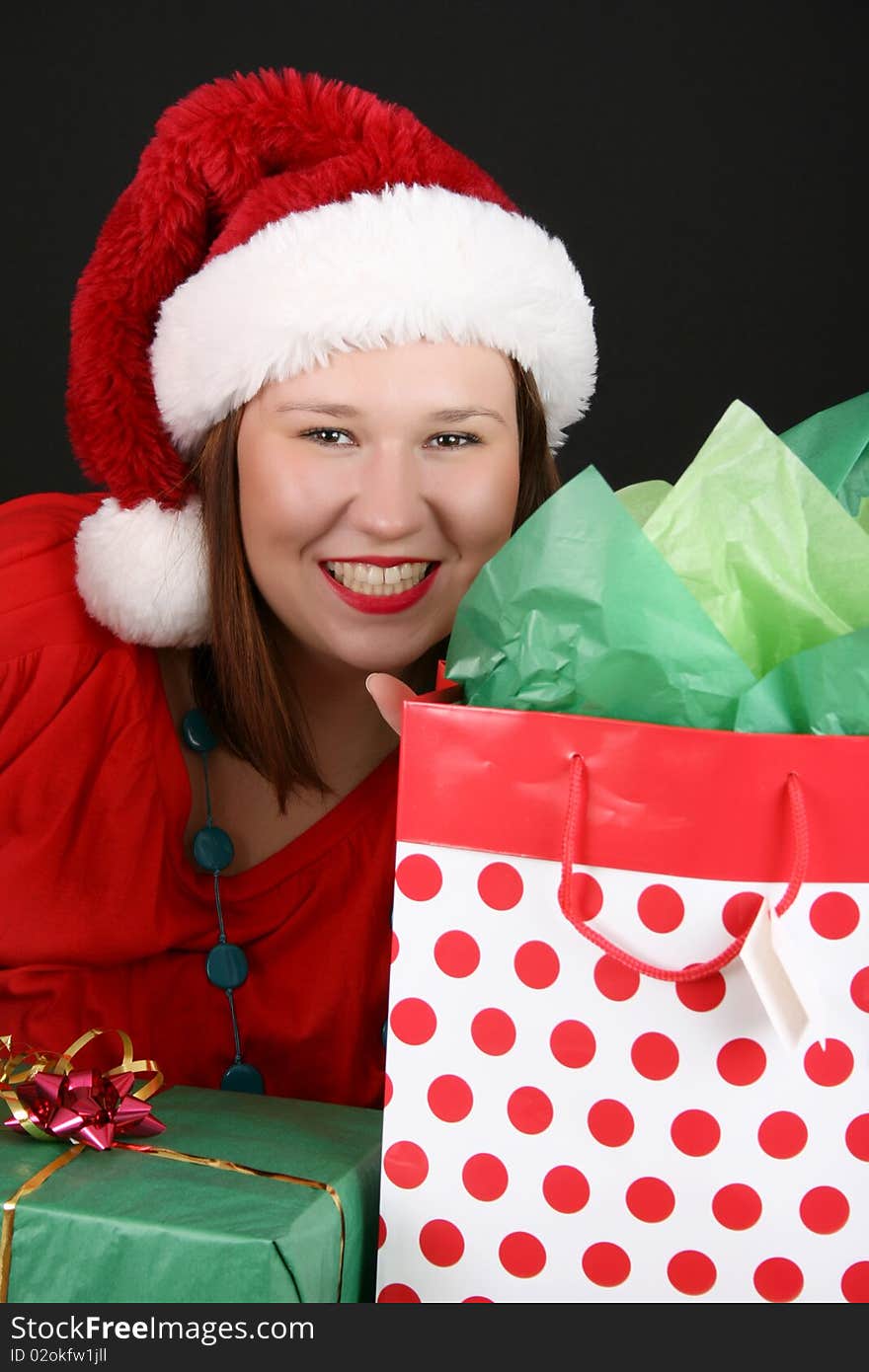 Beautiful brunette female with christmas gifts wearing a fluffy hat. Beautiful brunette female with christmas gifts wearing a fluffy hat