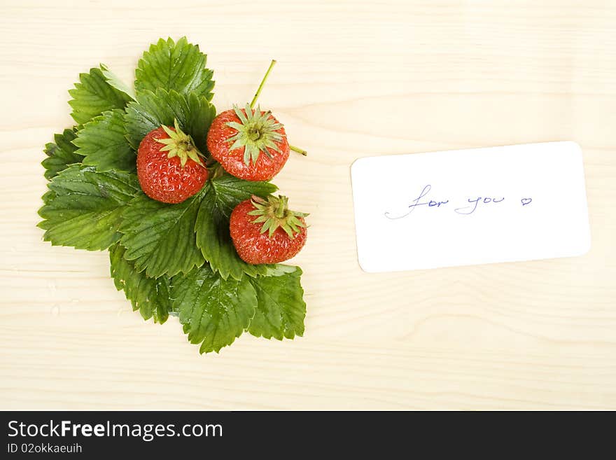 Juicy red strawberries and green leaves on the table next card is the text for you. Juicy red strawberries and green leaves on the table next card is the text for you