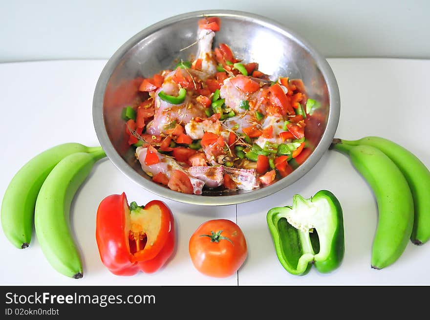 Dish with chicken all seasoned up for cooking with red and green pepper and green banana tomato. Dish with chicken all seasoned up for cooking with red and green pepper and green banana tomato