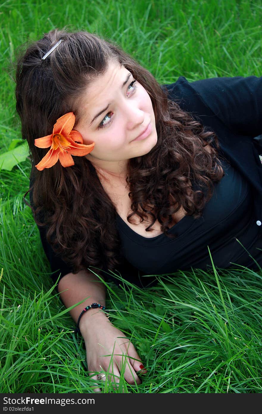 Girl the teenager about a flower, on a grass.