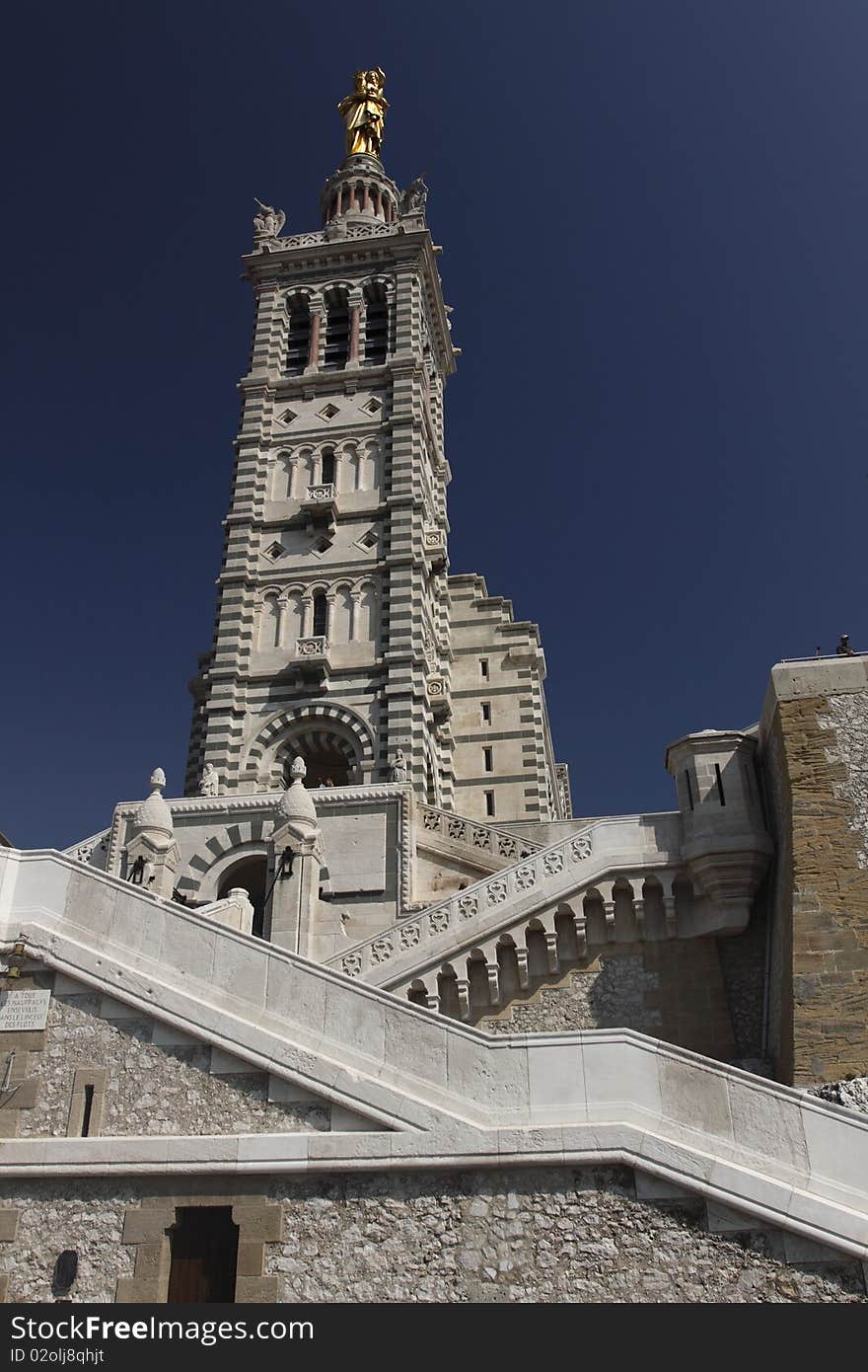 Notre-Dame de la Garde is a basilica located in Marseille, France. This ornate Neo-Byzantine church is situated at the highest natural point in Marseille, a 162 m (532 ft) limestone outcrop on the south side of the Old Port. As well as being a major local landmark, it is the site of a popular annual pilgrimage every Assumption Day (August 15). Notre-Dame de la Garde is a basilica located in Marseille, France. This ornate Neo-Byzantine church is situated at the highest natural point in Marseille, a 162 m (532 ft) limestone outcrop on the south side of the Old Port. As well as being a major local landmark, it is the site of a popular annual pilgrimage every Assumption Day (August 15).