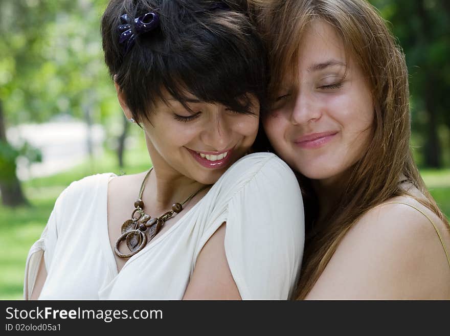 Two girlfrineds embracing outdoors