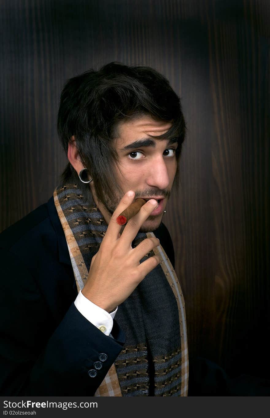 Portrait of young man with cigar on wooden background