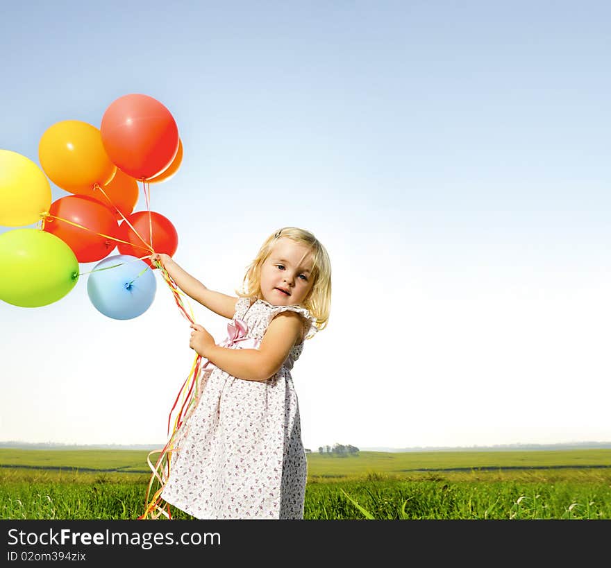 Adorable young girl holds tightly to a large bunch of helium filled balloons. Adorable young girl holds tightly to a large bunch of helium filled balloons