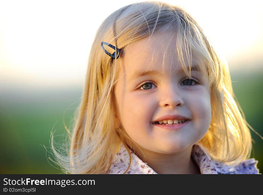 Beautiful blonde girl outside in a field with sunlight on her hair. Beautiful blonde girl outside in a field with sunlight on her hair.