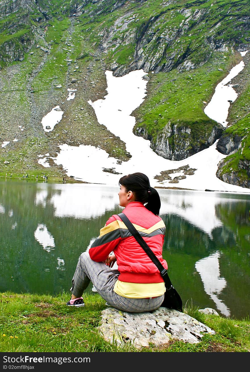 Woman sitting on a rock in a beautifull mountain scenery. Woman sitting on a rock in a beautifull mountain scenery