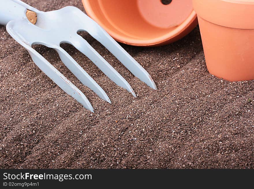 Steel rake on a ground near to ceramic pots. Steel rake on a ground near to ceramic pots.