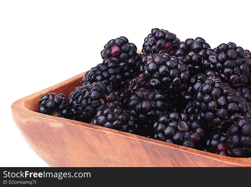 Blackberry - berries of black colour in a wooden plate on a white background. Blackberry - berries of black colour in a wooden plate on a white background.