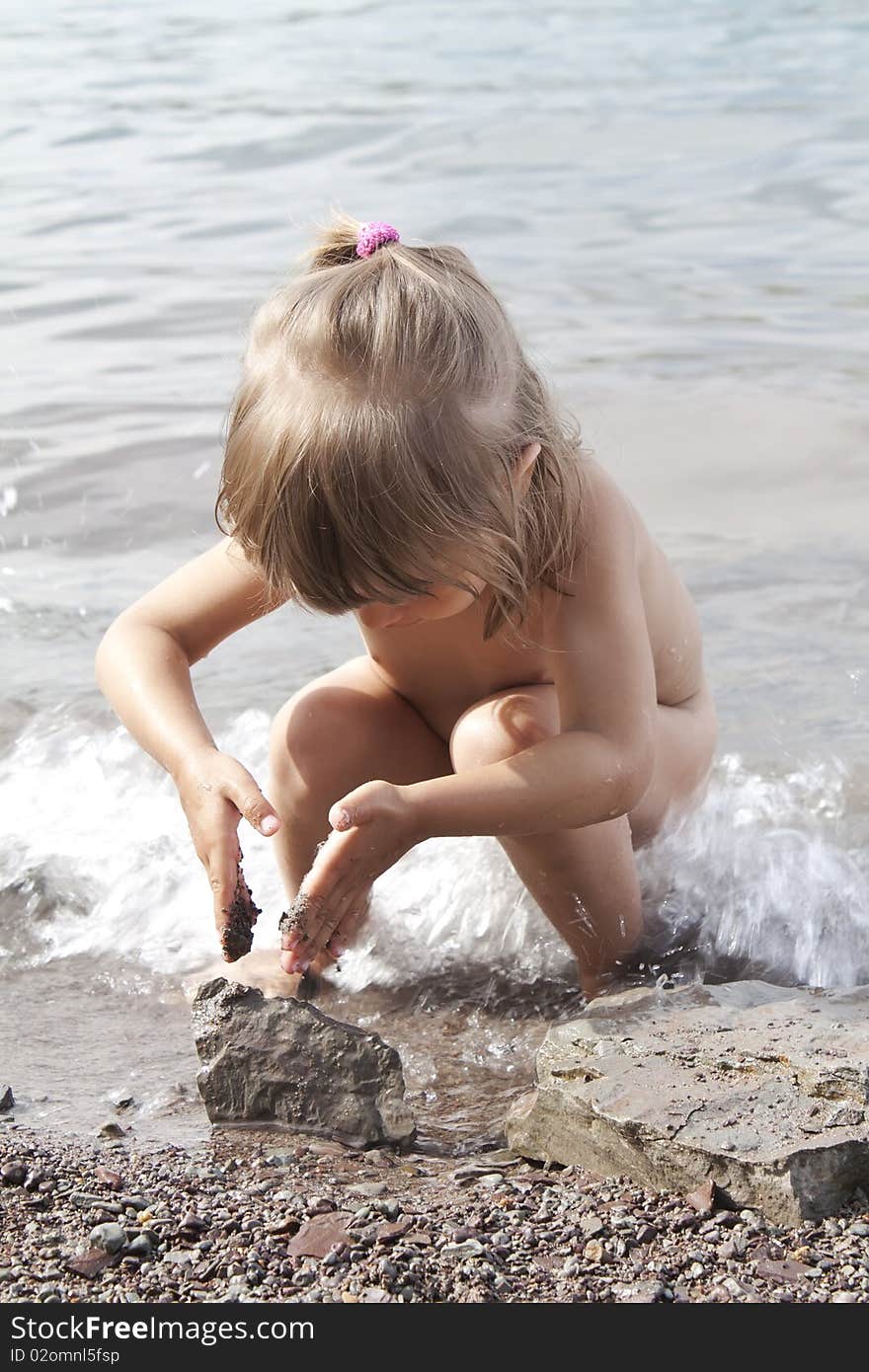 the girl plays coast with stones, the wave overflows feet. the girl plays coast with stones, the wave overflows feet